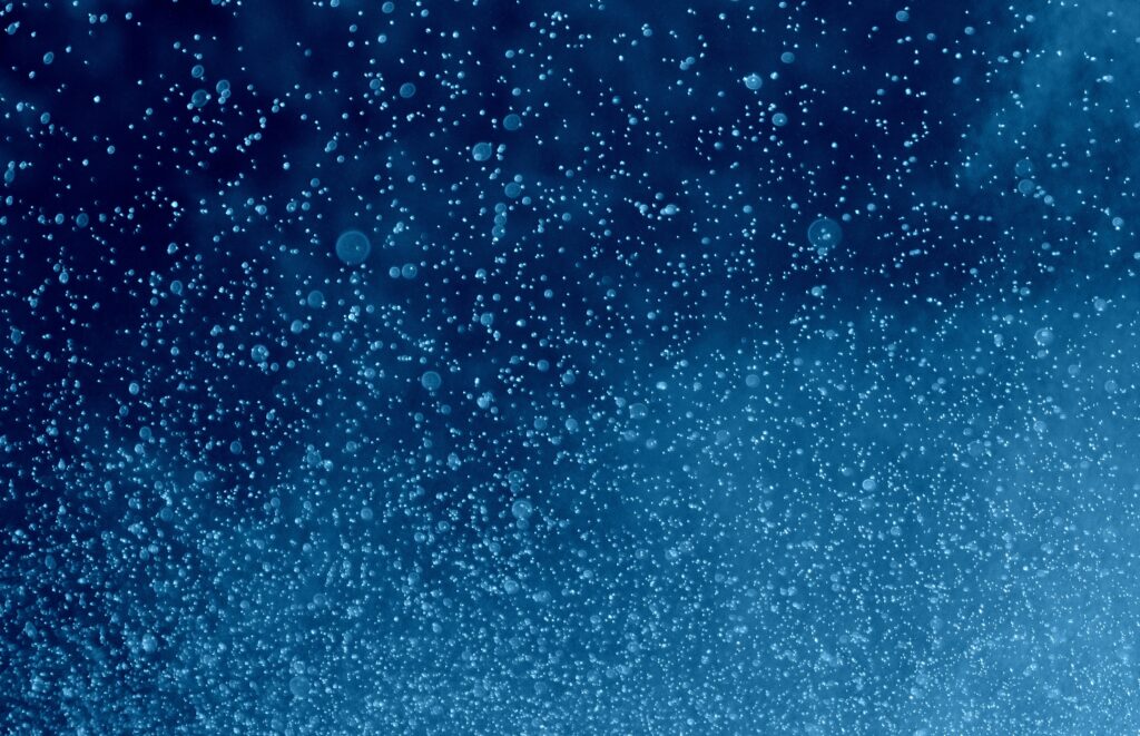 Soft blue water droplets floating in fluid motion, representing being held and sustained within the environment of early life